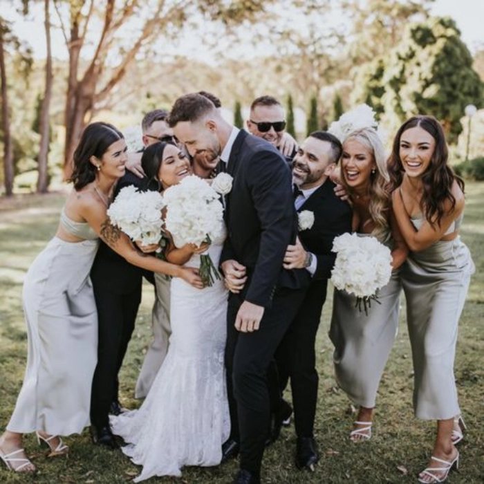 The bride and groom hugging their bridal party on the lawn, everyone laughing