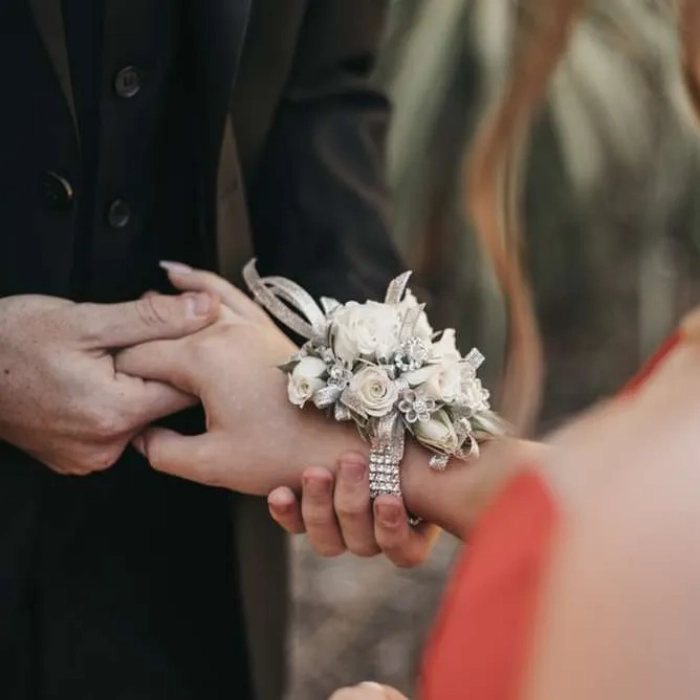 A wrist corsage of white flowers held between two hands