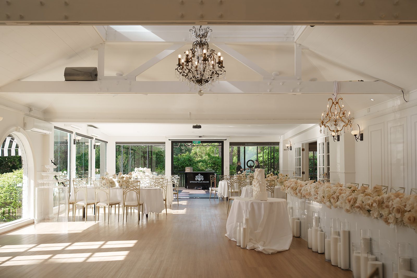 The Manor reception room in daylight, white walls, chandeliers and long tables