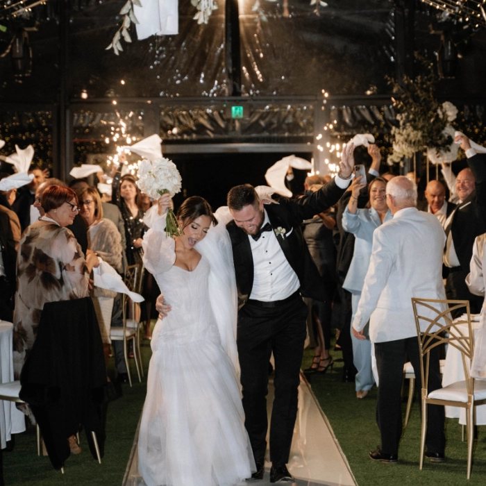 A couple making their entrance into The Pavilion as guests wave white napkins