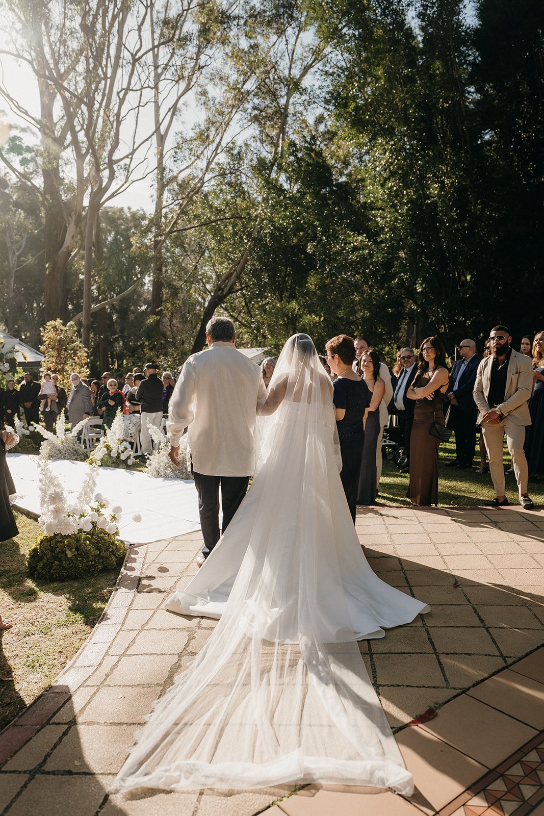 A couple walking back up the aisle through their guests in the gardens